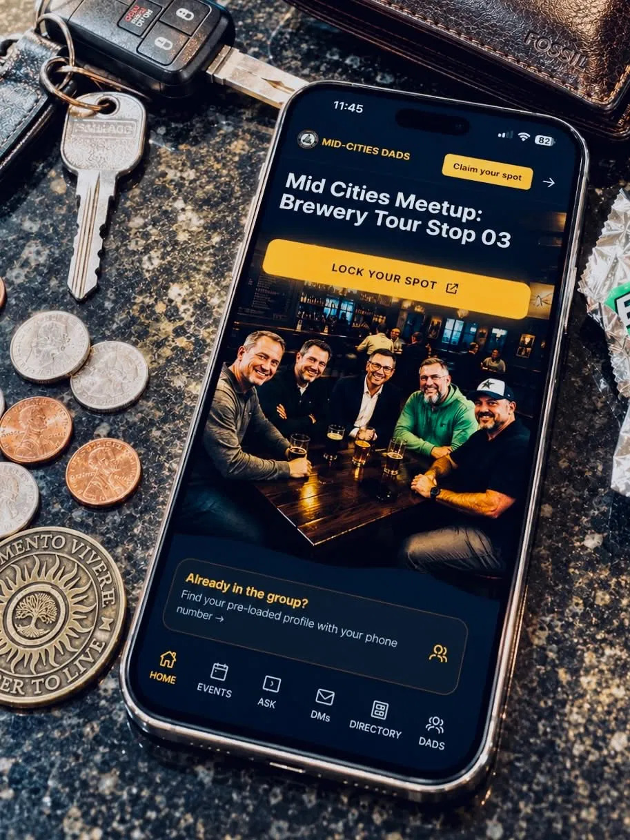The Mid-Cities Dads app on a phone beside keys and a wallet on a countertop.