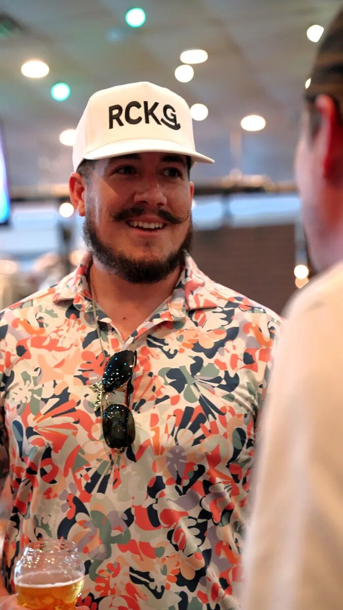 A dad in a floral shirt talking with another dad at Turning Point Beer