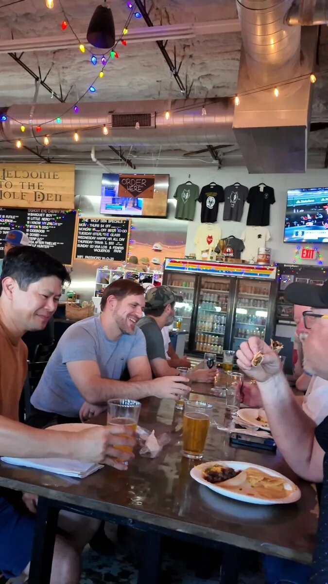 Dads seated together under string lights at False Idol Brewing